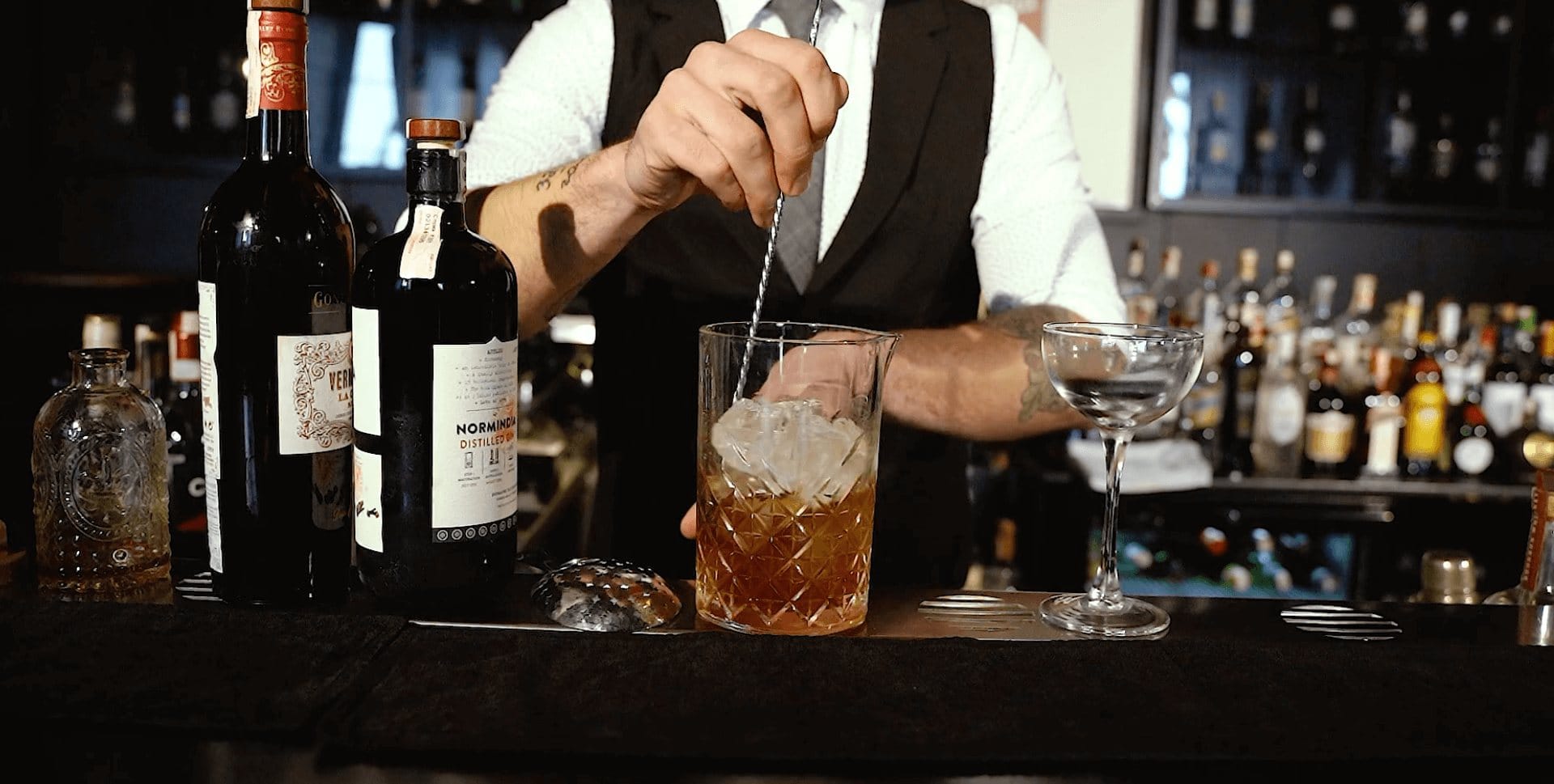 Barman míchá drink v mixing glass na baru